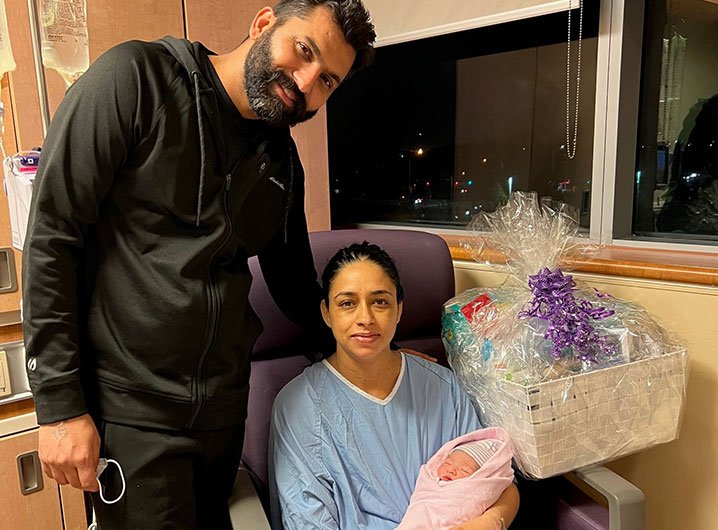 (l-r): Yadwinder Singh Bajwa stands beside Jasmeet Kaur Bajwa who is seated and holding a baby girl