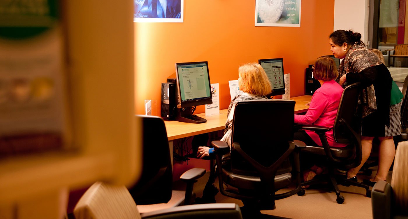 A librarian (far right) assists a staff member in their online research