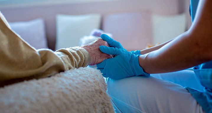 Clinical staff person holding an elderly patients hand