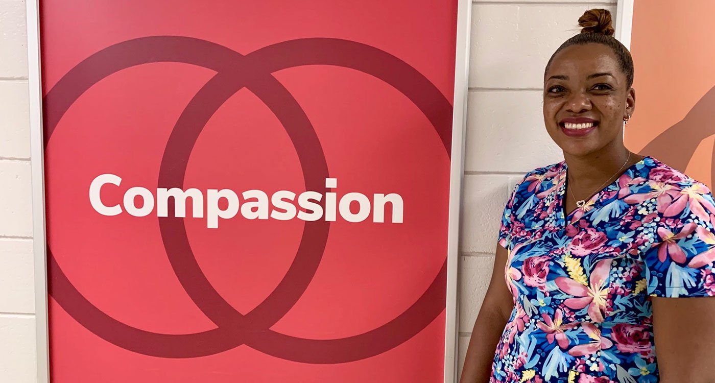 Registered Nurse Lanae Sylva stands in front of the Osler's Values compassion sign