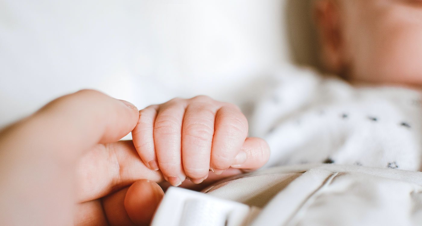 Infant holds onto mother's finger