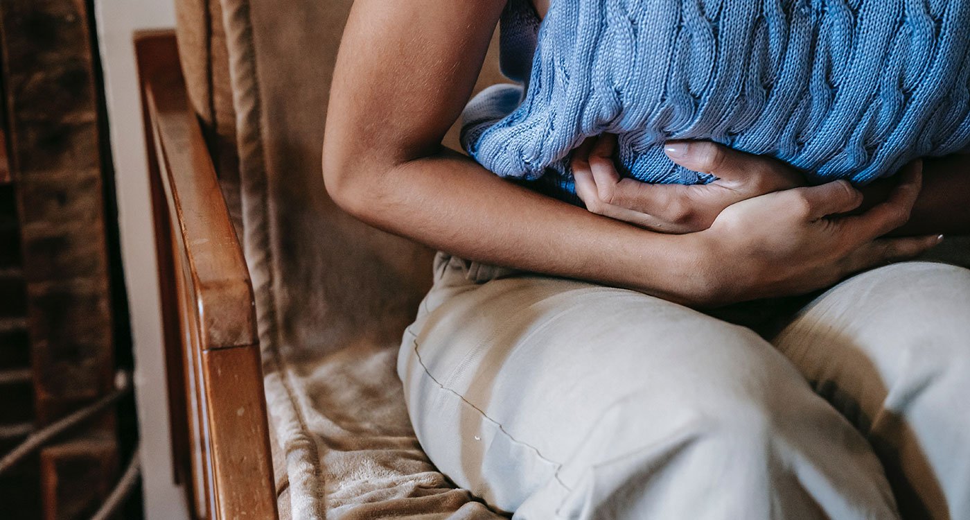 A person sits in a chair holding their stomach in pain