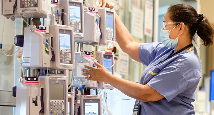 ICU staff member adjusts settings on IV monitor