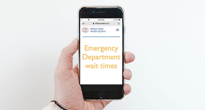 Hand holding cell phone showing the Emergency Department wait clocks webpage