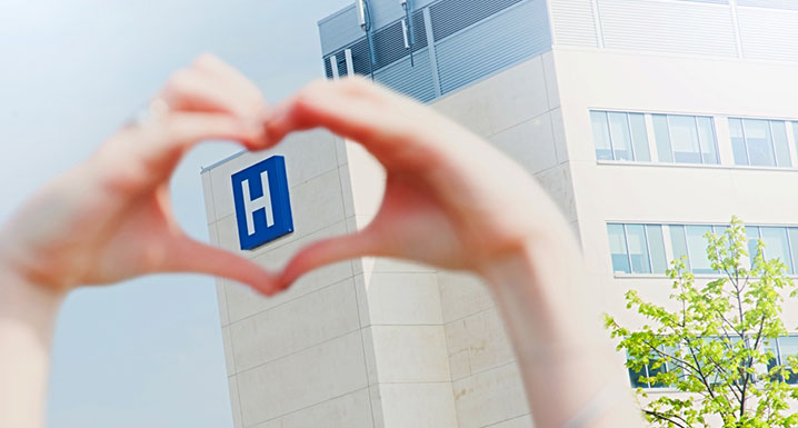 Heart hands around hospital sign