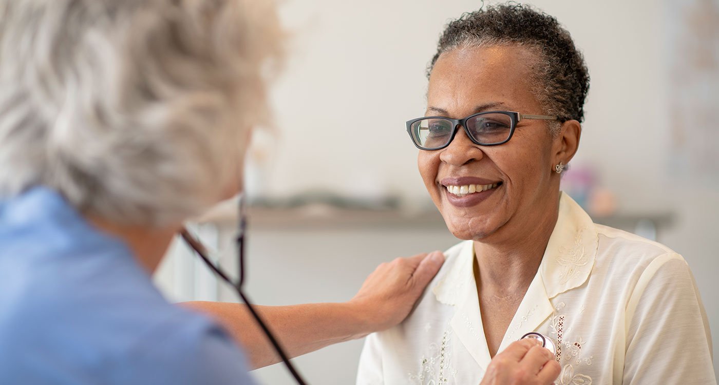 A physician checks a woman's heart with a stethoscope