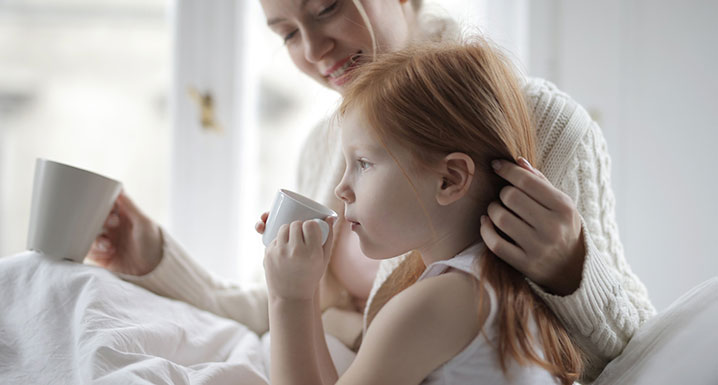 A mother and daughter sitting together and drinking tea