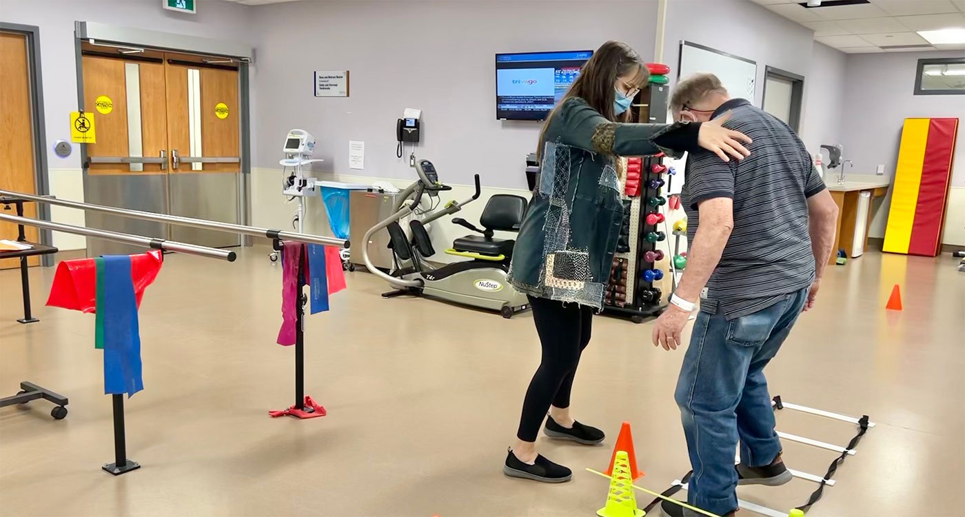 Amanda, a physiotherapist at the seniors clinic at Peel Memorial, helps a male patient with mobility exercises