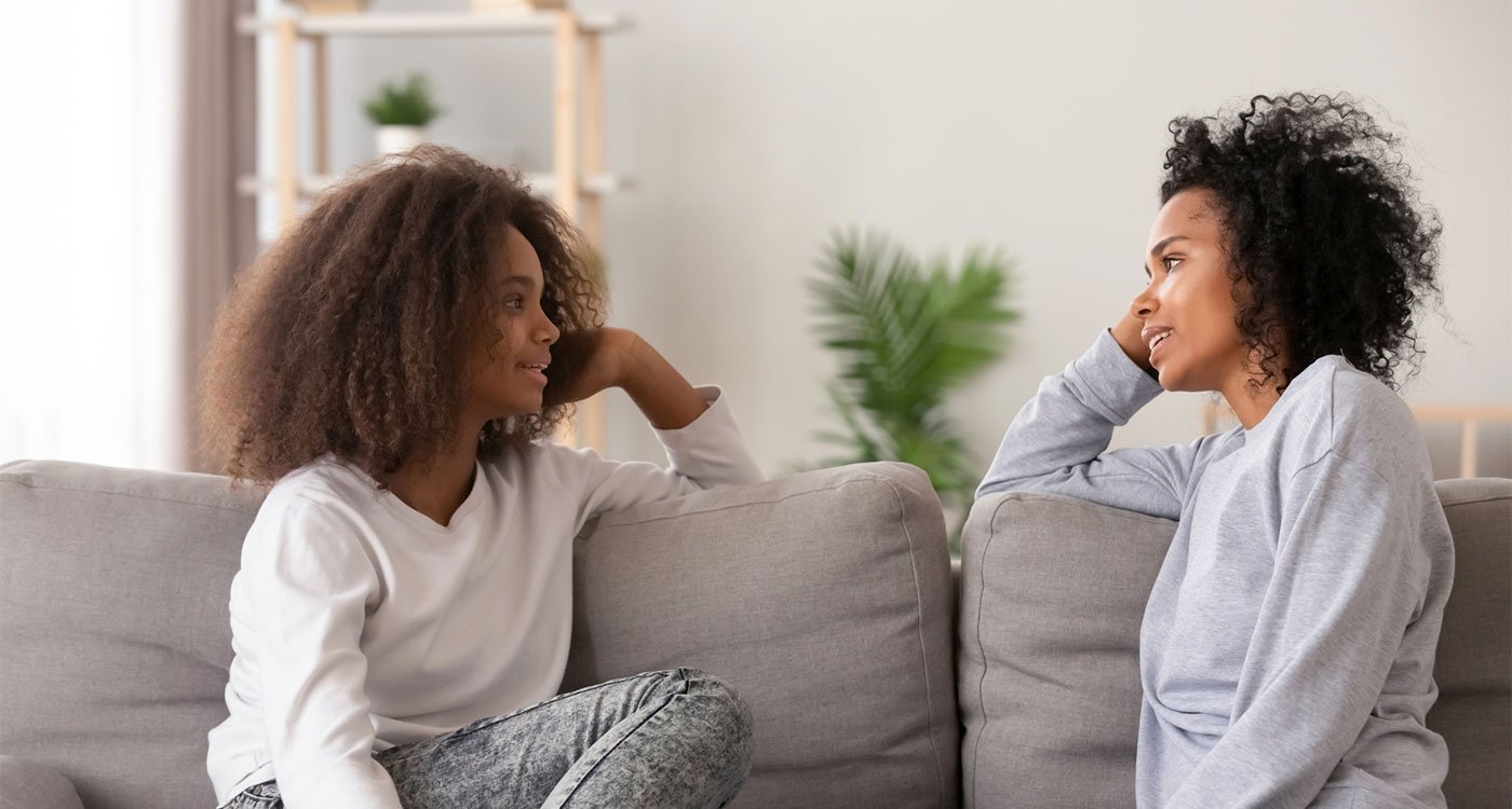 A mother and daughter sitting on a couch talking