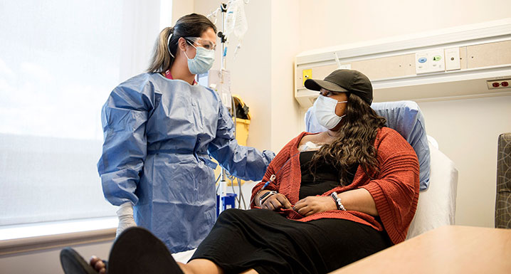 An Osler clinician caring for a patient while both are wearing masks