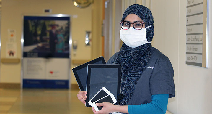 Dr. Humaira Saeed holding digital devices used for virtual visitation