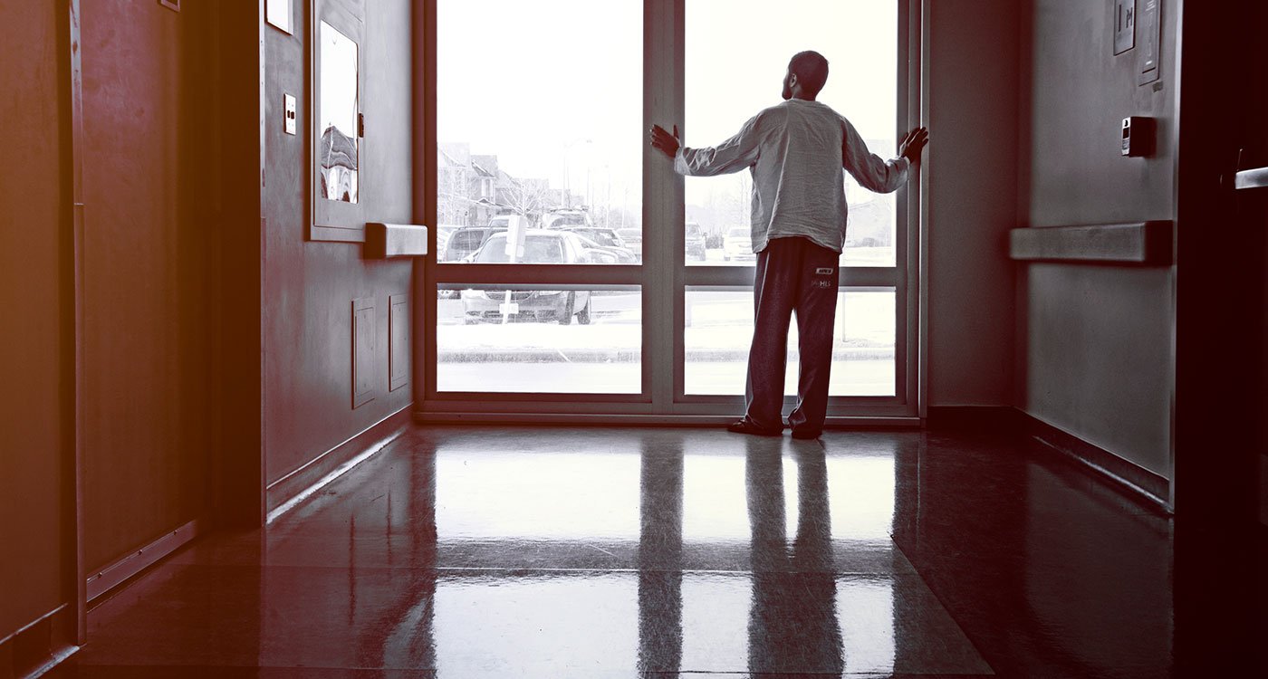A patient looks outside a hospital hallway window