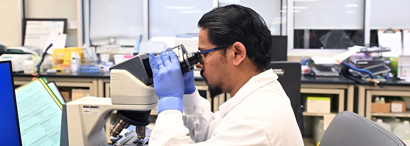 Male laboratory technician looking through microscope