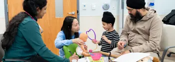 Two clinicians interact with a patient and their father in the Paediatrics Unit at Peel Memorial