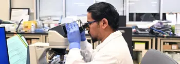 Male laboratory technician looking through microscope